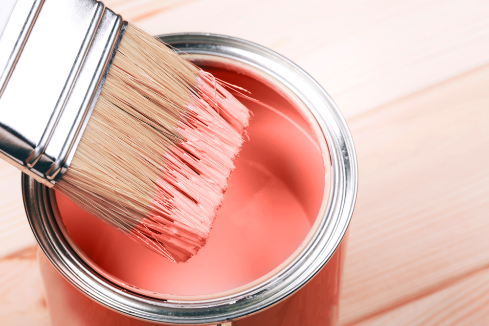 Brush with Living Coral paint on wooden background